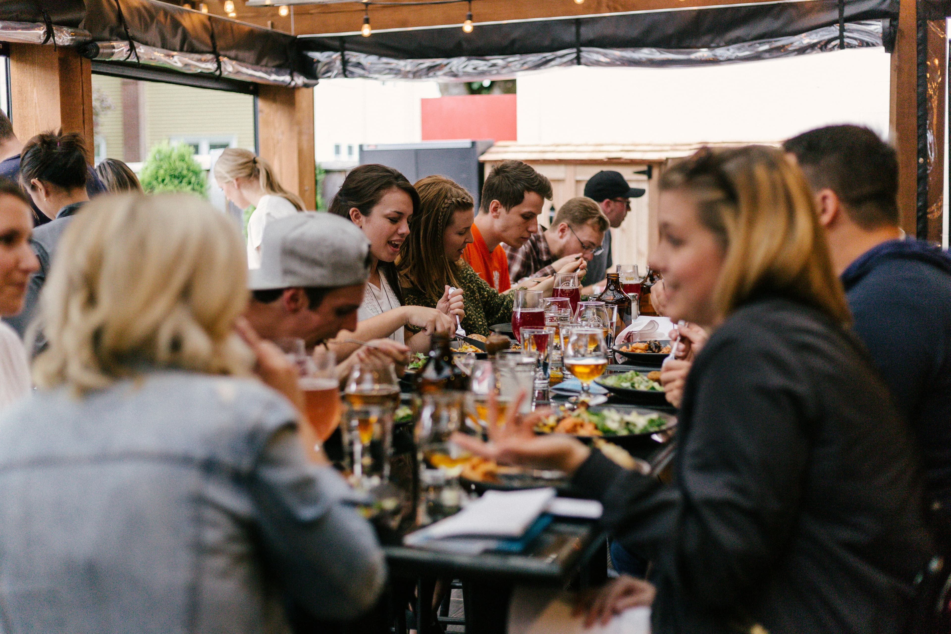 A lively restaurant patio full of guests enjoying happy hour together over drinks and shared plates